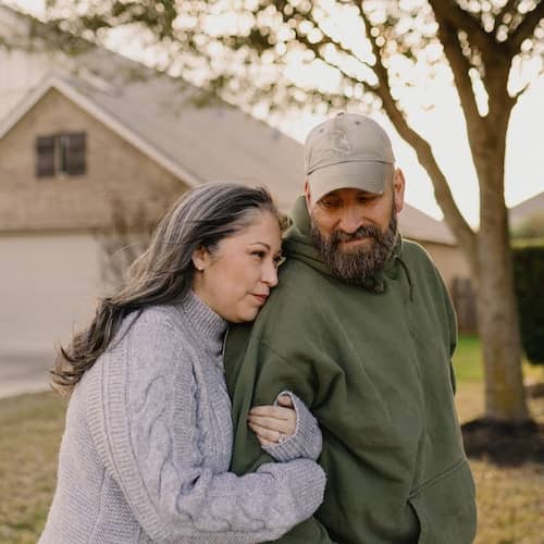 Woman holding man's arm while he looks her way.