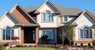 A traditional looking large red brick house with cream siding.