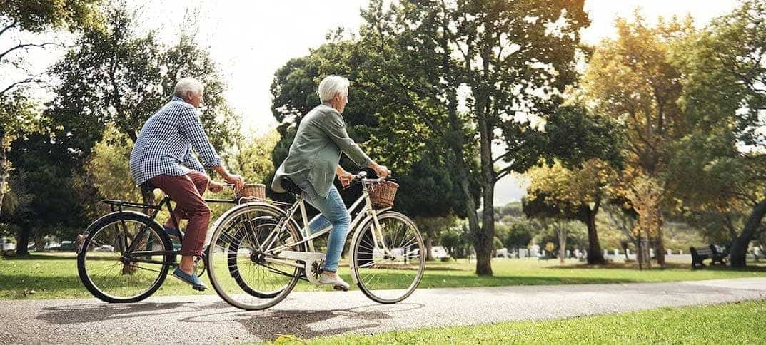 An outdoor scene in a park with seniors riding bikes, enjoying recreational activities.