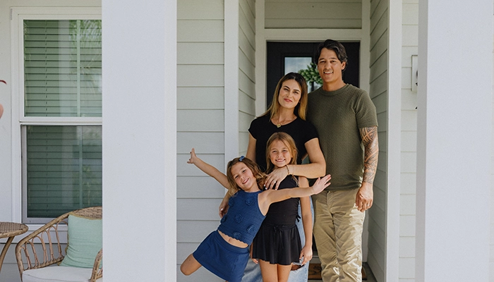 Parents and two daughters standing in their doorway smiling.