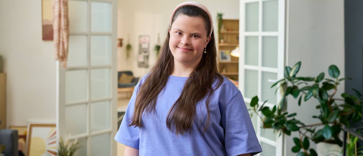 Young woman with Down Syndrome standing in study of her new home.