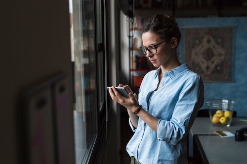 Woman at home checking status of loan on her smartphone.