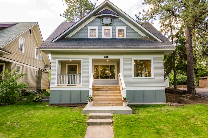 Exterior view of a cozy tan and gray Craftsman style home.