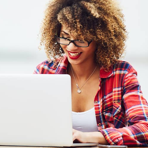 A woman wearing glasses working on a laptop, indicating digital work or studying.