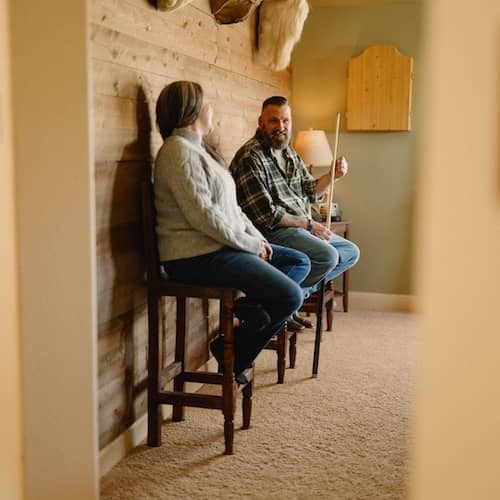 Couple sitting on stools smiling at each other.