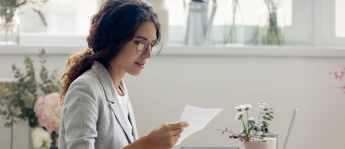 A woman looking at mail, potentially in a home or personal finance context.