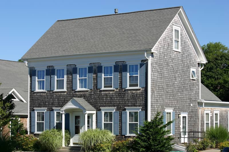 Two story cape cod style home with blue shutters.