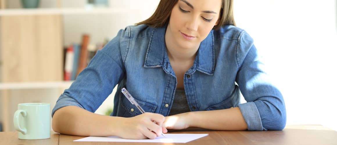 woman writing letter on table at home