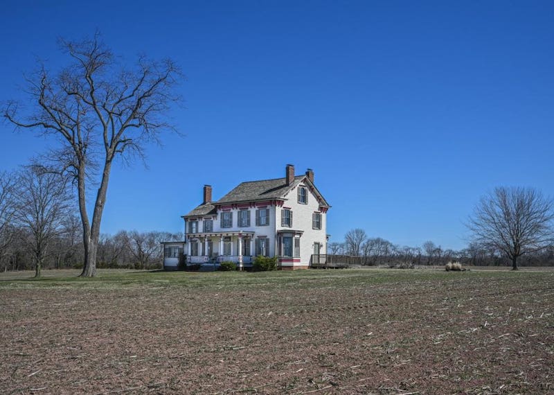 Historic white home in a large field.