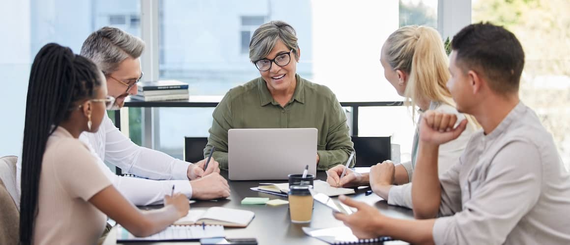 Team of multigenerational business colleagues meeting around a table.