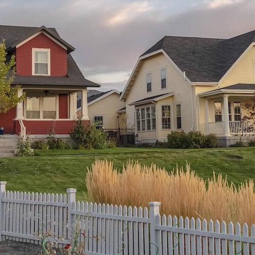 Wooden fence marking a property line with a lush green lawn and trees.
