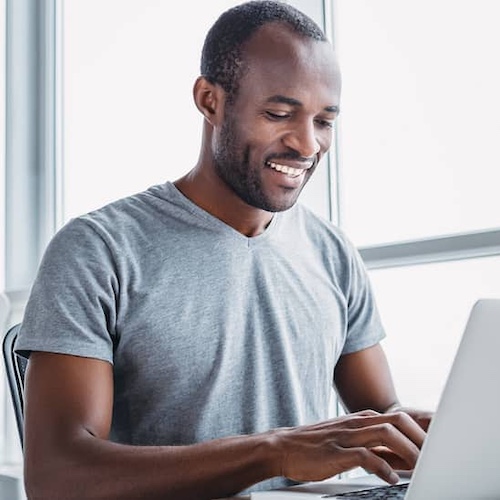 A man working on a laptop in a modern indoor setting.