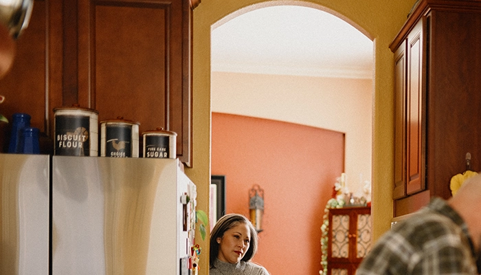 Woman watching husband cook on stove.