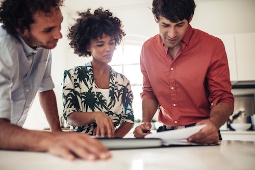 Couple meeting with realtor, reviewing paperwork.