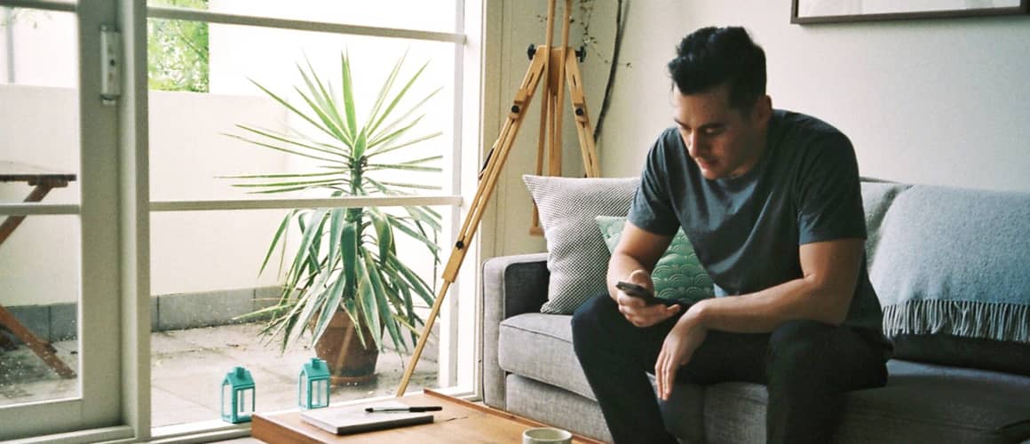 A person sitting on his home couch possibly looking at stocks.