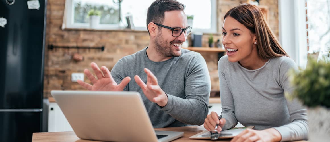 man and woman looking at laptop while man explains something and they smile