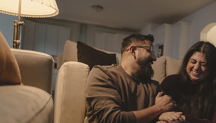 Couple holding each outher on floor near couch and laughing.