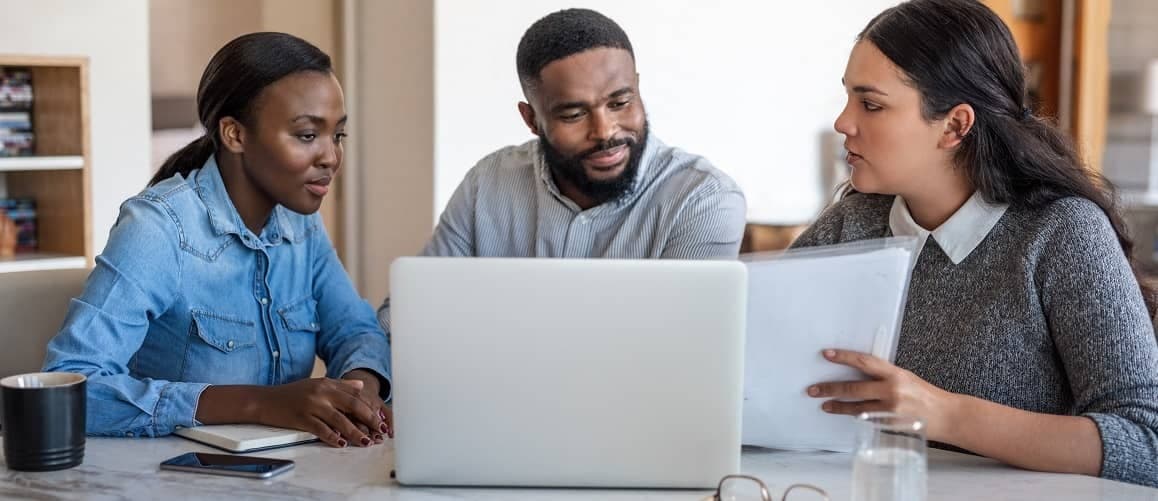 A couple discussing underwriting with a lawyer, possibly related to a mortgage process.