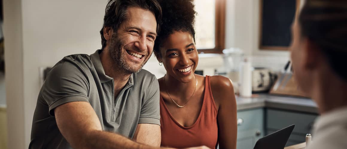 Couple smiling and shaking hands with a financial advisor.