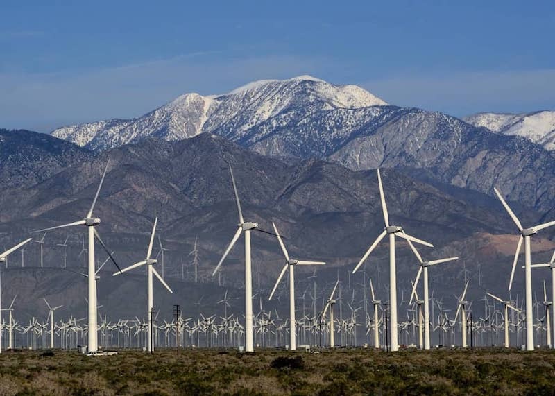 Wind turbines in a valley by a Mountain range.