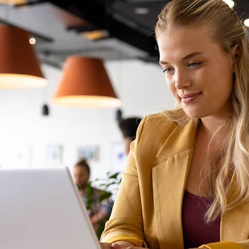 Woman sitting at open laptop at a cafe, smiling.