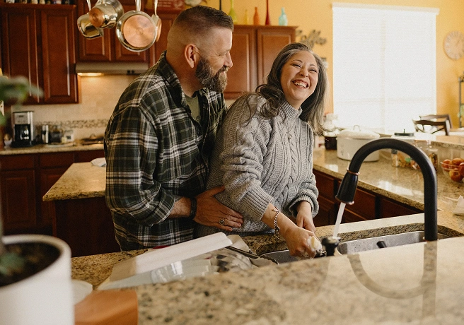 Couple standing together in a kitchen.