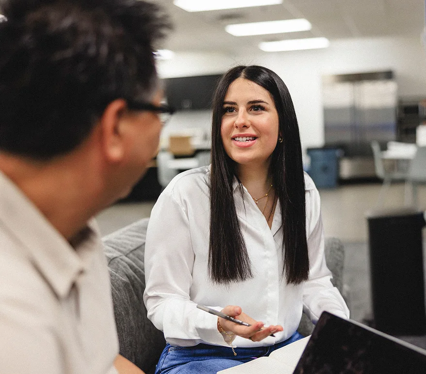 Two people face each other; one is in the foreground and the other in the background.