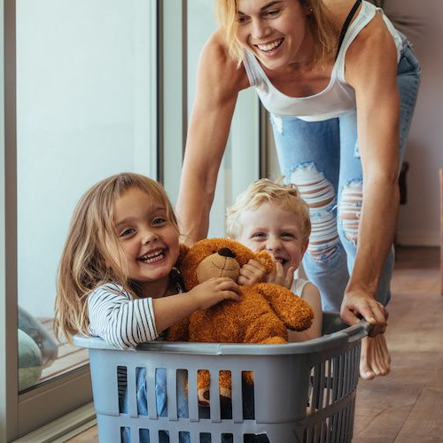 Image of mom pushing children in laundry basket during move-in.