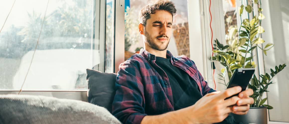 A man looking at his phone with somewhat surprised expressions.