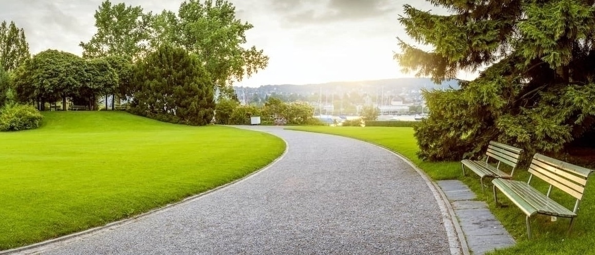 A view of a park in a city with track and benches.