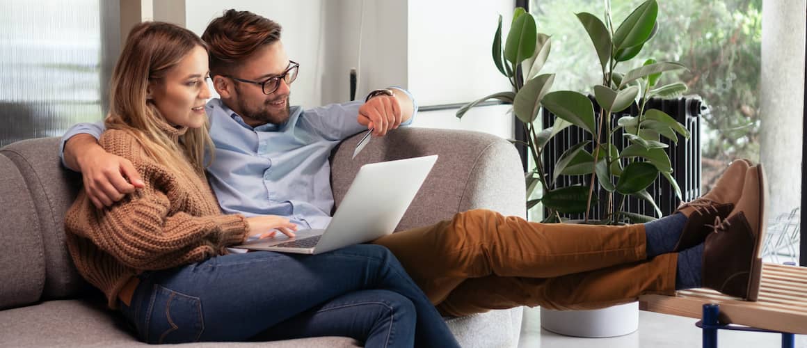 A couple possibly putting their credit card or some company card information on a laptop.