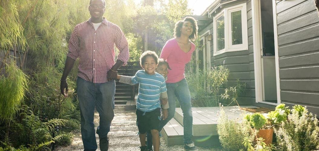 A family walking by a house, suggesting a family near or approaching a residential property.