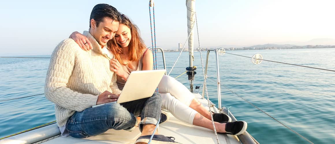 Couple on sailboat with laptop.