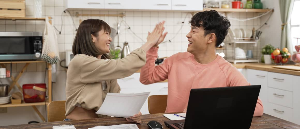 Couple high-fiving one another in kitchen.