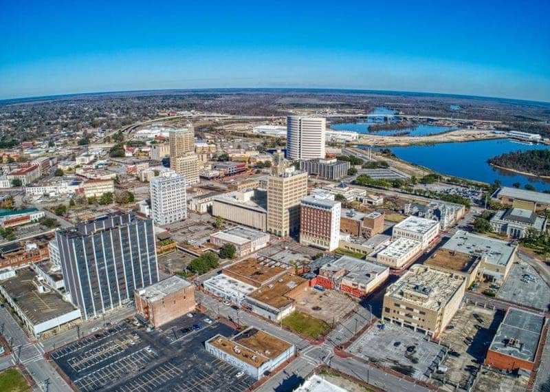 Aerial view of city in Jefferson County Texas featuring dense small buildings and bodies of water in the distance.