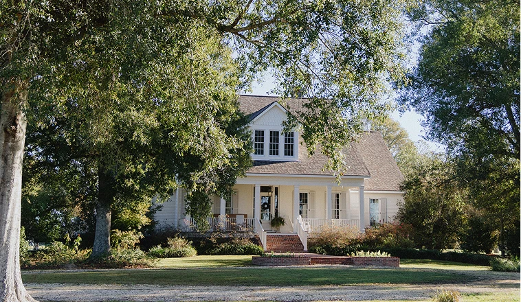 Large home with a front porch surrounded by trees.