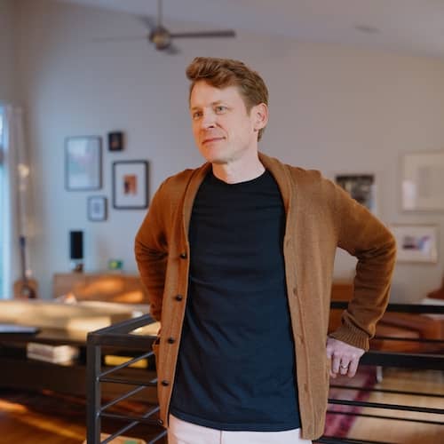 Man leaning on railing in home.