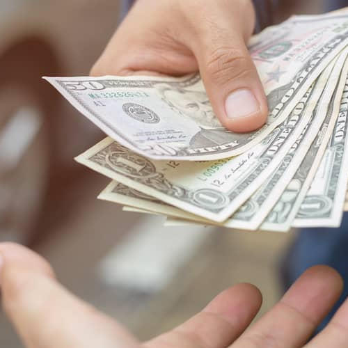A close-up of a person handing money to someone else.