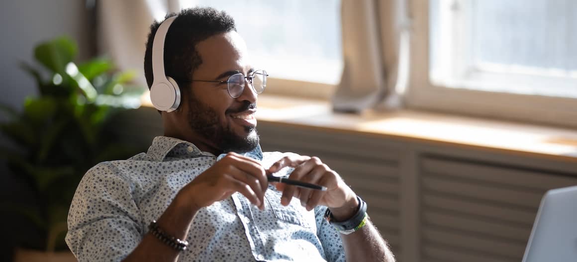 RHB Assets From IGX: Man listening to a podcast on headphones while relaxing at home.