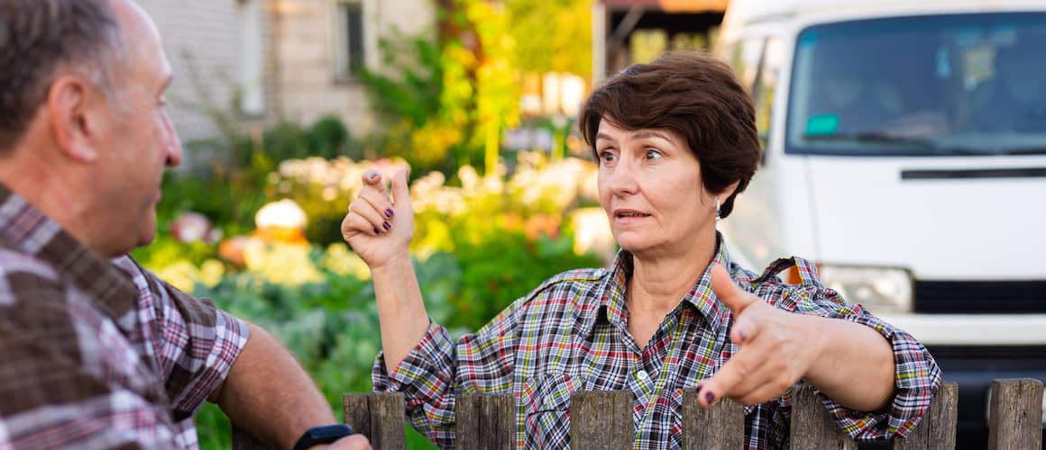 Image depicting neighbors chatting near a wooden fence.