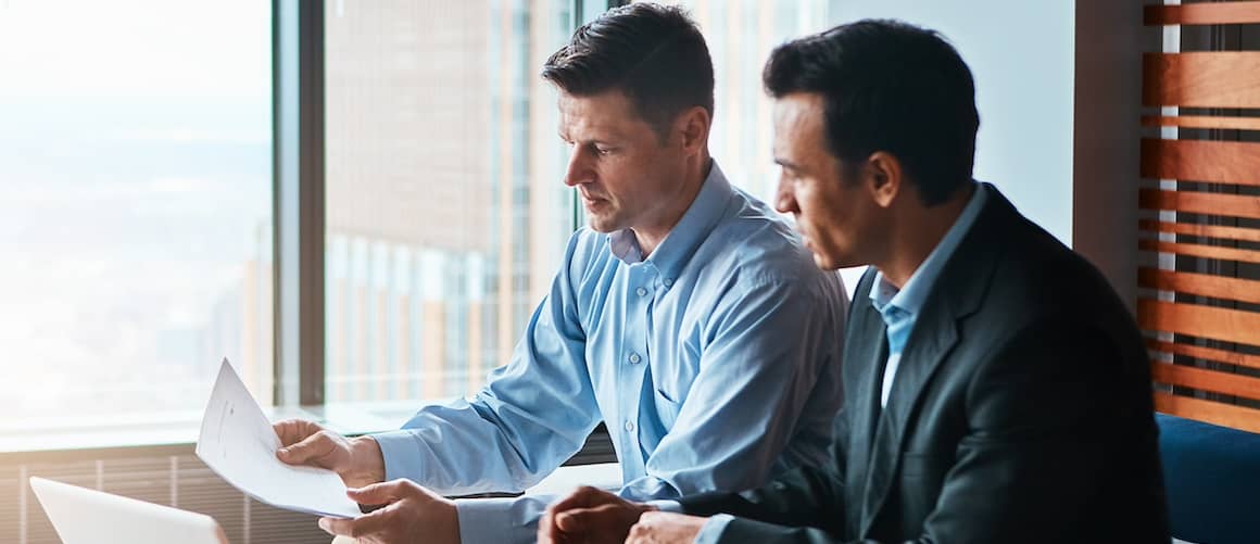 Two men going over paperwork together.