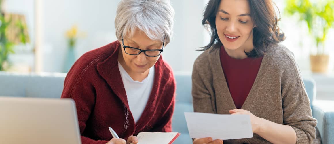 Mother and daughter reviewing documents and taking notes together.