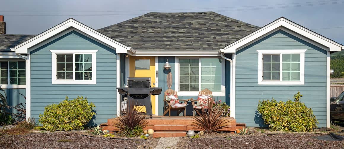 Small brown house with mulch lawn.