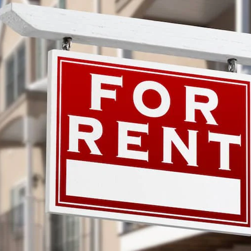 A for rent sign outside a line of houses.