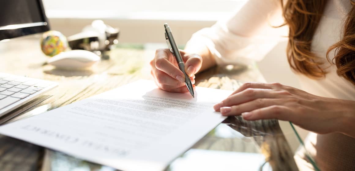A woman signing a contract, suggesting engagement in a real estate agreement or mortgage-related documentation.