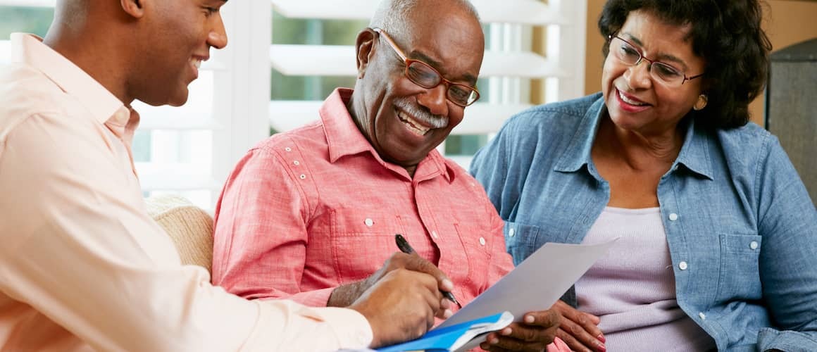 Financial planner meeting with older couple smiling in his office looking over retirement plan.