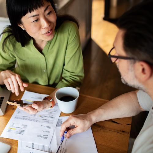 Couple looking at financial paperwork over coffee.