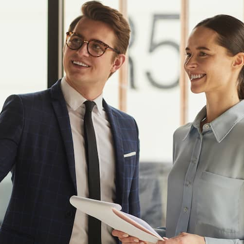 A real estate agent with a client holding a pad of paper, indicating a discussion or consultation.