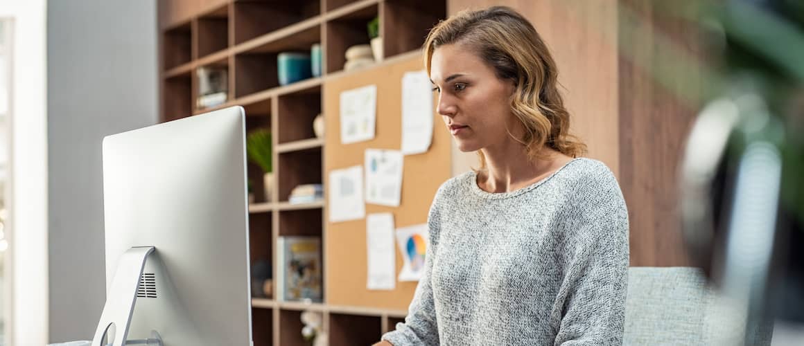 Image of woman on desktop computer reviewing financial statements.