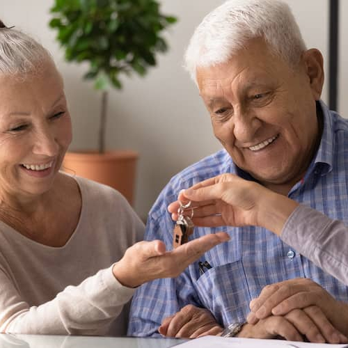 Excited Senior Husband And Wife Receive Keys In Realtor Office
